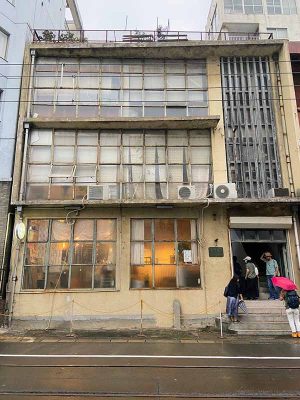 築町商店街の角地に建つ小野原本店。入母屋屋根の頂上の鬼瓦には「小」の文字が描かれている。地下にはレンガ造りの倉庫がある。「長崎って今も昔も、きっと土地が足りてないんですよね。だから、いろんなところを工夫して使ったんじゃないでしょうか」と大島さん。右側の「紅白まんじゅう」の看板があるのが附属屋で、レンガ造にモルタル仕上げ。主屋とは対照的な表情のファサードだ