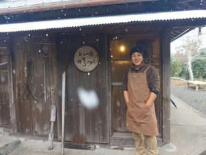 雪の中、宿の玄関前に立つオーナーの安達さん。この集落では家ごとに名前が付けられていて、「みちつじ」という屋号は、もともとこの家屋の立地が代々受け継ぐ名前だとか