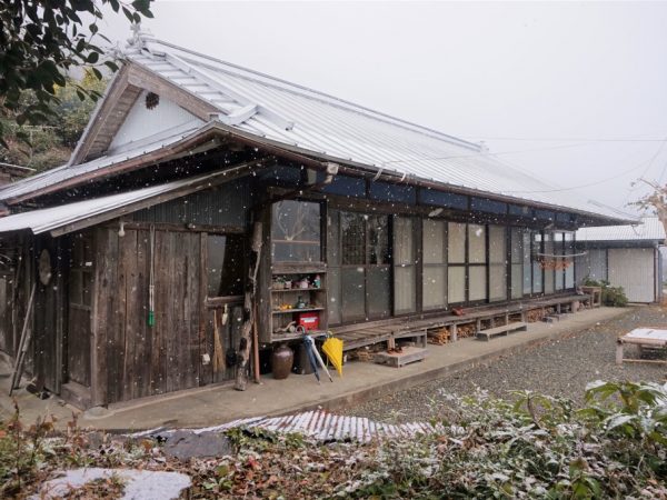 雪の中、宿の玄関前に立つオーナーの安達さん。この集落では家ごとに名前が付けられていて、「みちつじ」という屋号は、もともとこの家屋の立地が代々受け継ぐ名前だとか