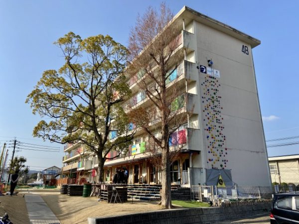 クライミングウォールを設けた「ひのさと48」。壁面に「48」と描かれている通り、もとは団地の48号棟だった建物だ。コミュニティカフェ、DIY工房、シェアキッチン、ビール醸造所を運営するほか、テナントとして認可保育園や子どもの発達支援施設、就労支援施設、ウクレレ制作工房が入居している。今後もテナントは増える予定