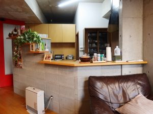 コンクリートブロックの壁で仕切られたキッチンはくの字型。裏側には和室がある