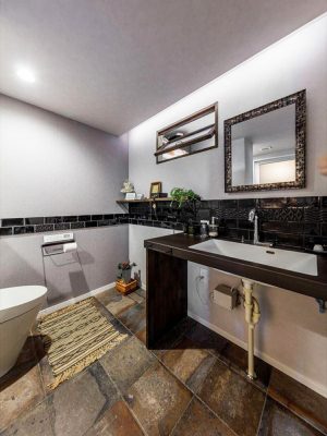終の棲家をつくるリフォームのトイレ部分。黒いタイルをあしらったシックな洗面台に、焼き物の床タイルをコーディネート（第8回トクラス選手権 最優秀賞/設計・施工：LOHAS studio 越谷）