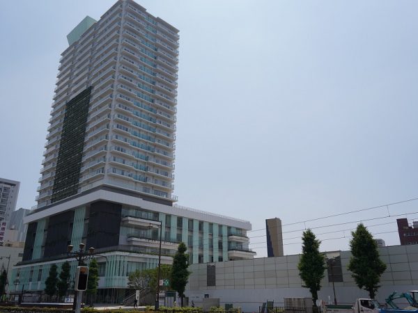 「emCAMPUS」東棟。1階にはフードホールとショップ、2・3階に市立図書館、4・5階にはオフィスや市役所の市民課窓口など行政機関、大学のサテライトオフィスなど、6～24階は分譲マンション、低層棟の屋上にはマンション居住者向け共有スペースとして農園を整備した。右側の工事中のところが西棟になる。また、「emCAMPUS」と駅前大通を挟んだ北側、2020年に閉店した「ほの国百貨店」の跡地も再開発でマンションなどが入る大規模施設を予定した工事が進行中