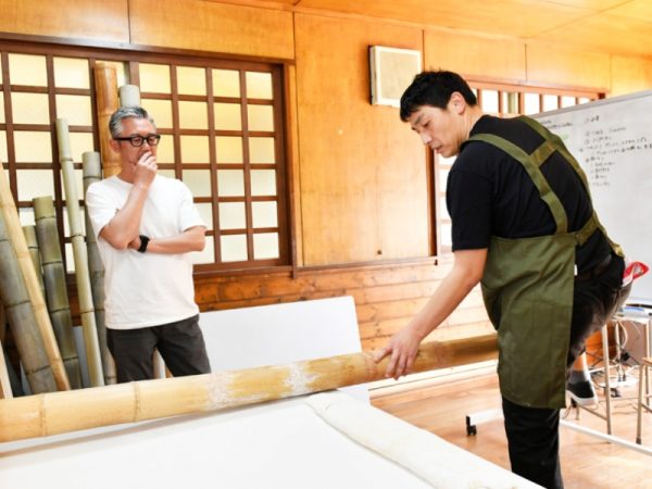佐野らーめんの伝統技法「青竹打ち」の指導を受ける研修生