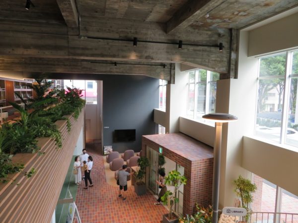 ロビーからの吹き抜けに面したつどにわライブラリー。カウンターデスクにはコンセントもあり、仕事にいそしめる。本棚の背後は1階営業室の吹き抜けだ