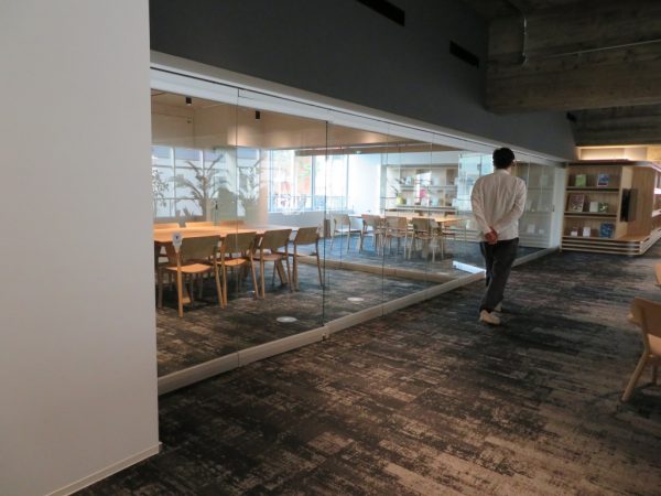 ロビーからの吹き抜けに面したつどにわライブラリー。カウンターデスクにはコンセントもあり、仕事にいそしめる。本棚の背後は1階営業室の吹き抜けだ