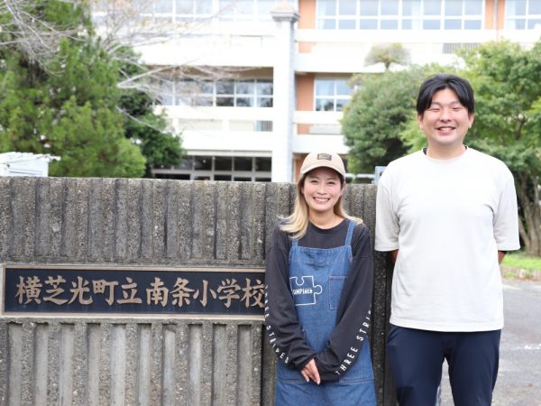 お話をお聞きした、株式会社運動会屋　地域共創事業部　部長でキャンピース横芝光の校長の飯田健史さんと、キャンピース横芝光スタッフの大木美穂さん。「リピーターで来てくださったお客様がお嬢さんをほかのキャンプ場に連れて行ったら『このキャンプ場の校長先生は誰なの？』と不思議がっていたそうです。そのお嬢さんはキャンプ場に校長先生がいると思っているということですよね。そういう話をお聞きすると、お嬢さんの心に何かが刻まれた証だと思ってうれしいですね」と飯田さん。「学校という立地からか安心感があり、ファミリーでのご利用が多いですね。親御さんが安心してお子様を遊ばせられるキャンプ場だと思います。スタッフがフォローしますので、初めてキャンプをする方にもぜひ遊びに来ていただきたいですね」と大木さん