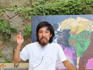 バイソンギャラリー入り口の前で。西村氏の後ろの絵は動物のバイソンを描いたもの