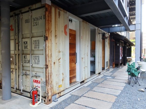 公道から建物を見たところ。格子の壁の裏にコンテナ、長屋がある。格子は周囲に合わせるためのデザイン