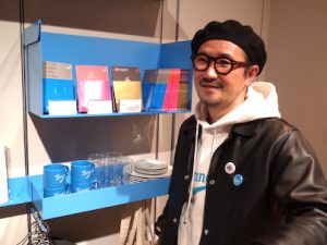 岡村さん。左の棚の冊子は特集上映に合わせてつくる。中身も濃い