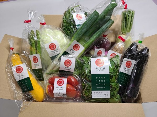 スイデンテラスを背景に長岡氏。来ているTシャツは自らデザインして作ったもの