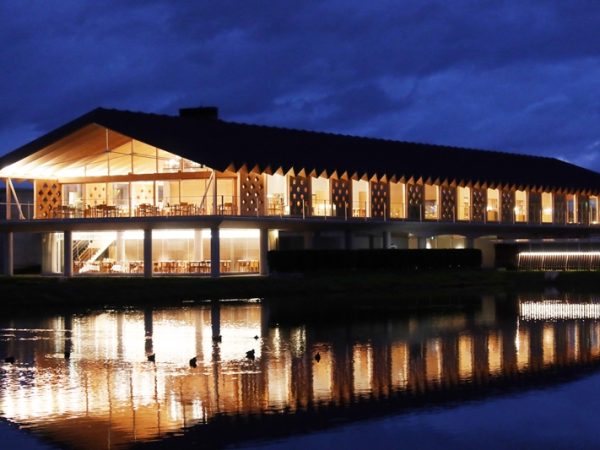 スイデンテラスを背景に長岡氏。来ているTシャツは自らデザインして作ったもの