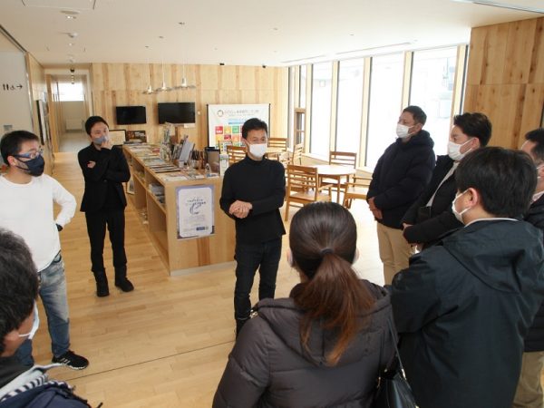 視察イベントの参加者に説明する村上さん（奥中央）