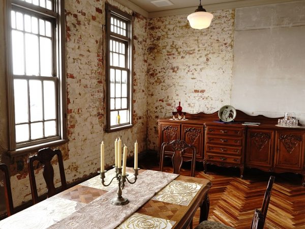 2階個室。レンガ組みが分かる壁と、テーブルなどのインテリアの雰囲気がぴったり。床は新しくしている。画像には写っていないがドアは薄い緑色のペンキが塗られている。これは古い建物を研究している専門家によると、進駐軍が接収したときに塗ったのではないかとのこと。建具にペンキを塗ること、色彩感覚からそう推察されるそうだ。だがそれによって、素材の木が保護され、100年前の建具のまま残っている理由となった可能性もあるのだとか