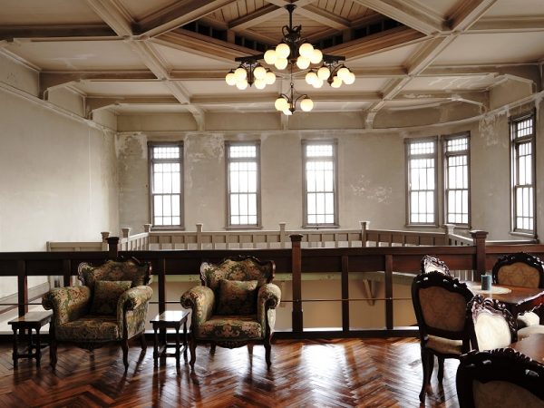 2階個室。レンガ組みが分かる壁と、テーブルなどのインテリアの雰囲気がぴったり。床は新しくしている。画像には写っていないがドアは薄い緑色のペンキが塗られている。これは古い建物を研究している専門家によると、進駐軍が接収したときに塗ったのではないかとのこと。建具にペンキを塗ること、色彩感覚からそう推察されるそうだ。だがそれによって、素材の木が保護され、100年前の建具のまま残っている理由となった可能性もあるのだとか