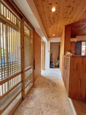 ▲“閉じつつ開く”の工夫は随所に見られる。南西側に面した駐車スペースの壁面は風通しの良い花ブロックに。その周りに植えられたハイビスカスが日よけになっている。「有孔コンクリートブロック（花ブロック）は、日中の日射しを遮断するほか、目隠し効果もあるため、防犯対策をしながら開放部を実現しています。また、風が孔を通り抜けるので、台風の時はコンクリートで強度を保ちつつ強風のバッファー（緩衝）としても重要な役割を果たします」