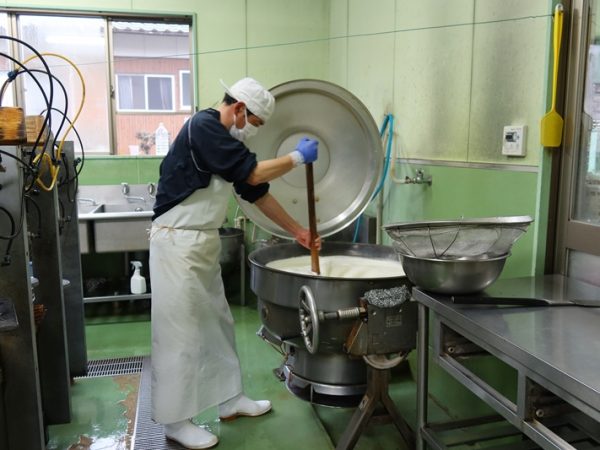 人が手で大きな木べらを使ってかき混ぜ続けるという地味な作り方