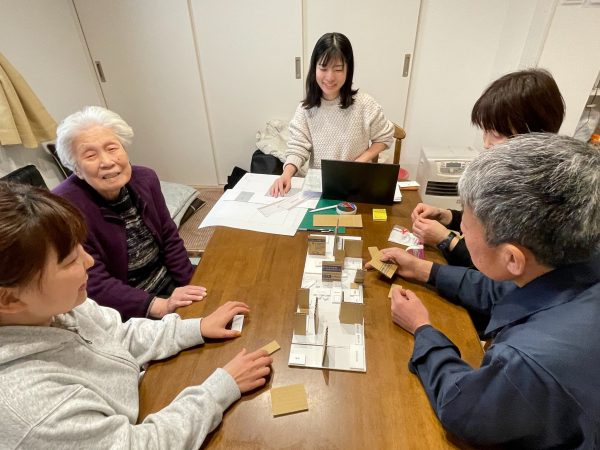 家族揃って話し合いながら、模型の壁や家具などを動かして間取りを検討していく。VUILDの一級建築士、中西朱理さん（写真中央）も同席してアドバイスした。３月以降、家族はみなし仮設住宅で暮らしている（写真／介川亜紀）　