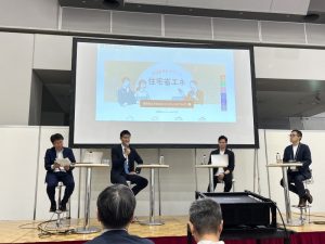 シンポジウムの様子。左からRing-ndx（株）代表取締役 蔭山貴弘氏、環境大臣政務官 参議院議員 朝日健太郎氏、（株）LEALIAN代表取締役 佐藤俊氏、Ring-ndx（株）戸部素尚氏。Ring-ndx（株）はマンション管理のコンサルティングを、（株）LEALIAN小型バッテリーのシェアリングモデルを基にした電カネットワークの構築を手がけている
