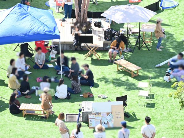 ▲リノベーションまちづくりのプログラム「リビングスクール」で提案された市内公共空間を利活用する社会実験事業「トライアルパーク」の様子。霧島市民会館前の広場に人工芝を敷設しベンチやハンモック、移動式遊具などを設置したところ、「こういうスペースがほしかった」と市民にも好評で現在まで延長している