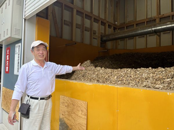 藤和那須リゾート株式会社 飯泉 グループマネージャー。写真の木質チップは自社所有林の間伐等にて発生したもので燃料となる。