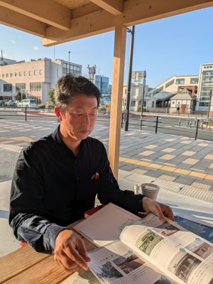 地域おこし協力隊の松本さん。寄居の魅力をYottecoにあるパンフレットを使って紹介する