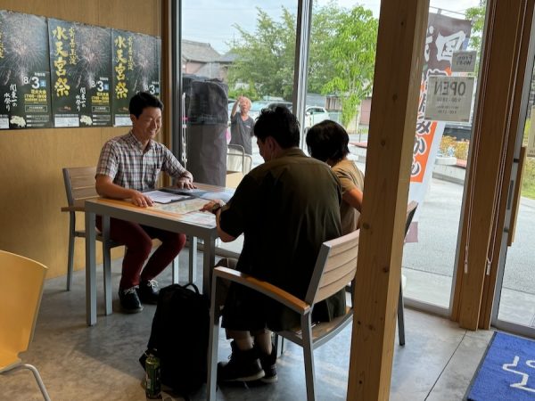 地域おこし協力隊の松本さん。寄居の魅力をYottecoにあるパンフレットを使って紹介する