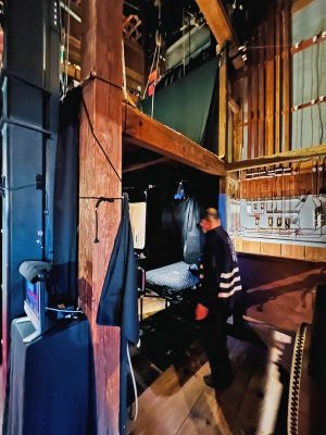 ▲下手袖の様子。音響や照明には電動の機材を使っているが、その他の舞台装置はすべて昔ながらの“手動”で行う。客席に設置された空調の吹出し口も、袖でロープを引きながら広告看板を開閉して調整しているというから驚きだ。「実は、平成の大修理の前はエアコンもトイレも無い状態。夏の館内は灼熱地獄だったので、慌ててエアコンを設置しましたが、それだけで約300万円の出費となり赤字状態だったようです（笑）」と石橋さん