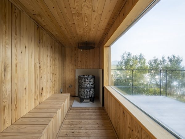 左にウッドデッキ、離れがある。母屋は左側に小さなキッチン的空間、収納があり、右側の２つのドアはいずれもサウナへの入口（撮影/八代写真事務所）