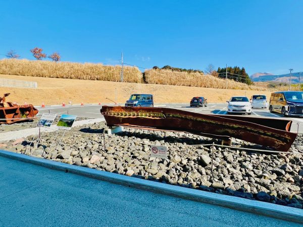 ▲駐車場前には、熊本地震で崩落した阿蘇大橋の鉄骨の一部が展示されているが、実際の崩落現場（南阿蘇村河陽）では今も橋げたが峡谷に引っかかったままの状態で残されており、震災遺構として見学できるようになっている