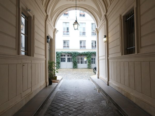 最初に見学したのは右手、青い扉の先にある薄いグリーンの扉の物件。建物の前に停まっているのが不動産会社のマダムの車