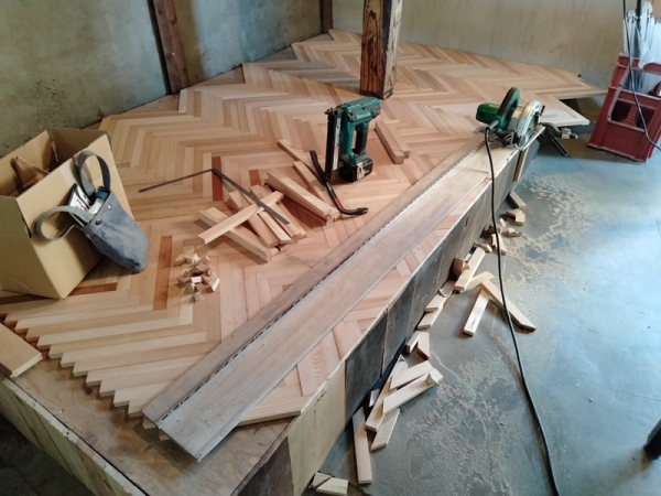 一段上がったところに仕事スぺースを設けた。へリンボーン状に床材を貼っているところ。難しそうだ（写真提供：みのもけいこ）