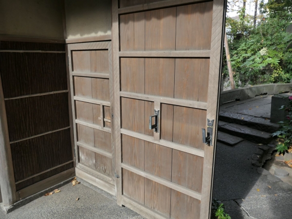 門の壁は練壁、下部が脇扉の高さに合わせて杉皮を張り詰めている。脇扉のヘリには鉈目削の装飾が

