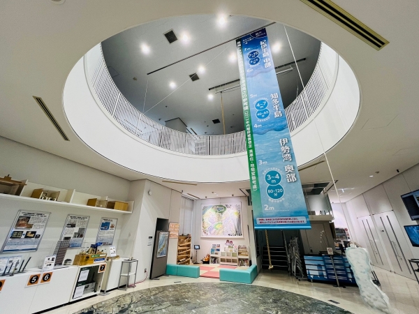 ▲2層吹抜けの減災ギャラリーには、南海トラフ巨大地震発生時における津波の高さの参考値が懸垂幕で展示されている。津波の危険性については数字でぼんやりと理解していたつもりでも、実際にこの高さを見上げてみると怖さを感じる