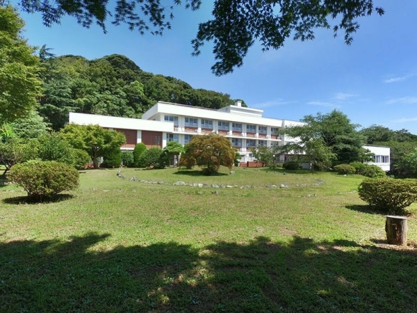 広々とした青空と緑が生い茂る山を背景に立つ、白を基調にしたアルペなんみんセンターの施設。広大な庭はよく手入れがされていて、とても心地よさそうな印象だ