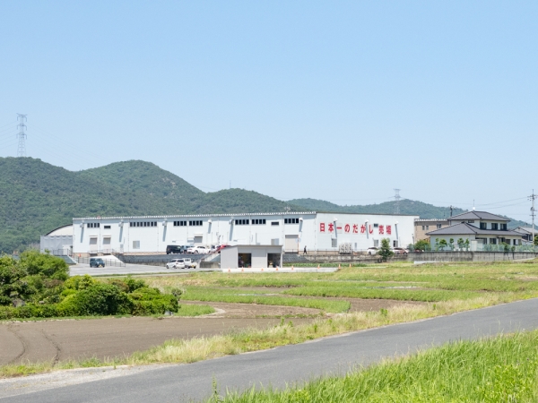 日本一のだがし売場は田畑が広がる郊外に立地し、工場のような巨大な建物をしている
