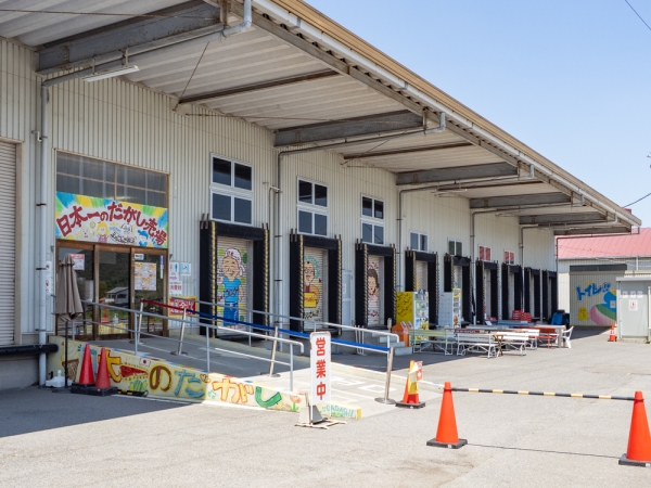 日本一のだがし売場は田畑が広がる郊外に立地し、工場のような巨大な建物をしている
