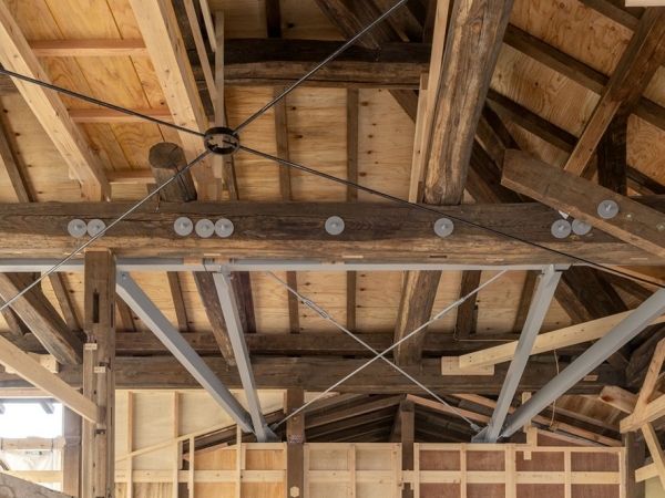 表座敷の小屋組みの補強工事の様子。グレーの鉄骨部材は今回の補強。手前の交差するブレース材はもともとあったものを復原したもの（写真：NARU建築写真事務所）