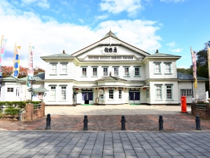 国重要文化財の「康楽館」。1910年（明治43年）、小坂鉱山の厚生施設として誕生した国内最古級の木造芝居小屋で、外観は洋館風、内装は典型的な和風芝居小屋という和洋折衷の造りが特徴。今もなお現役の芝居小屋として春から秋の常打芝居や、毎年恒例の歌舞伎などが公演されている