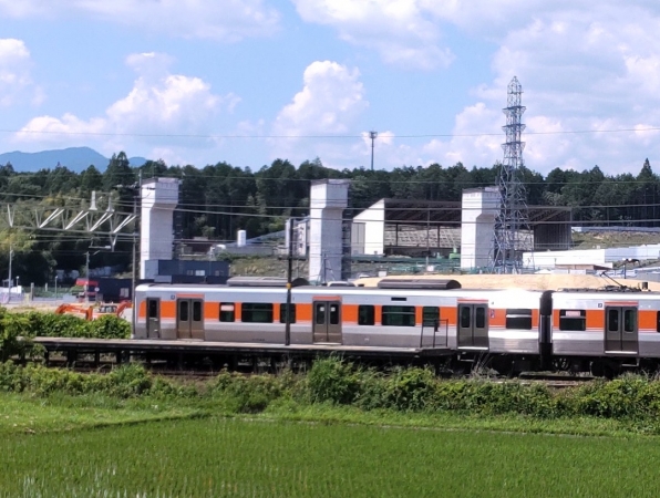 JR中央線の車両が行き交う背後に広がる岐阜県駅（仮称）建設現場。駅ホームの橋脚などの工事が進む